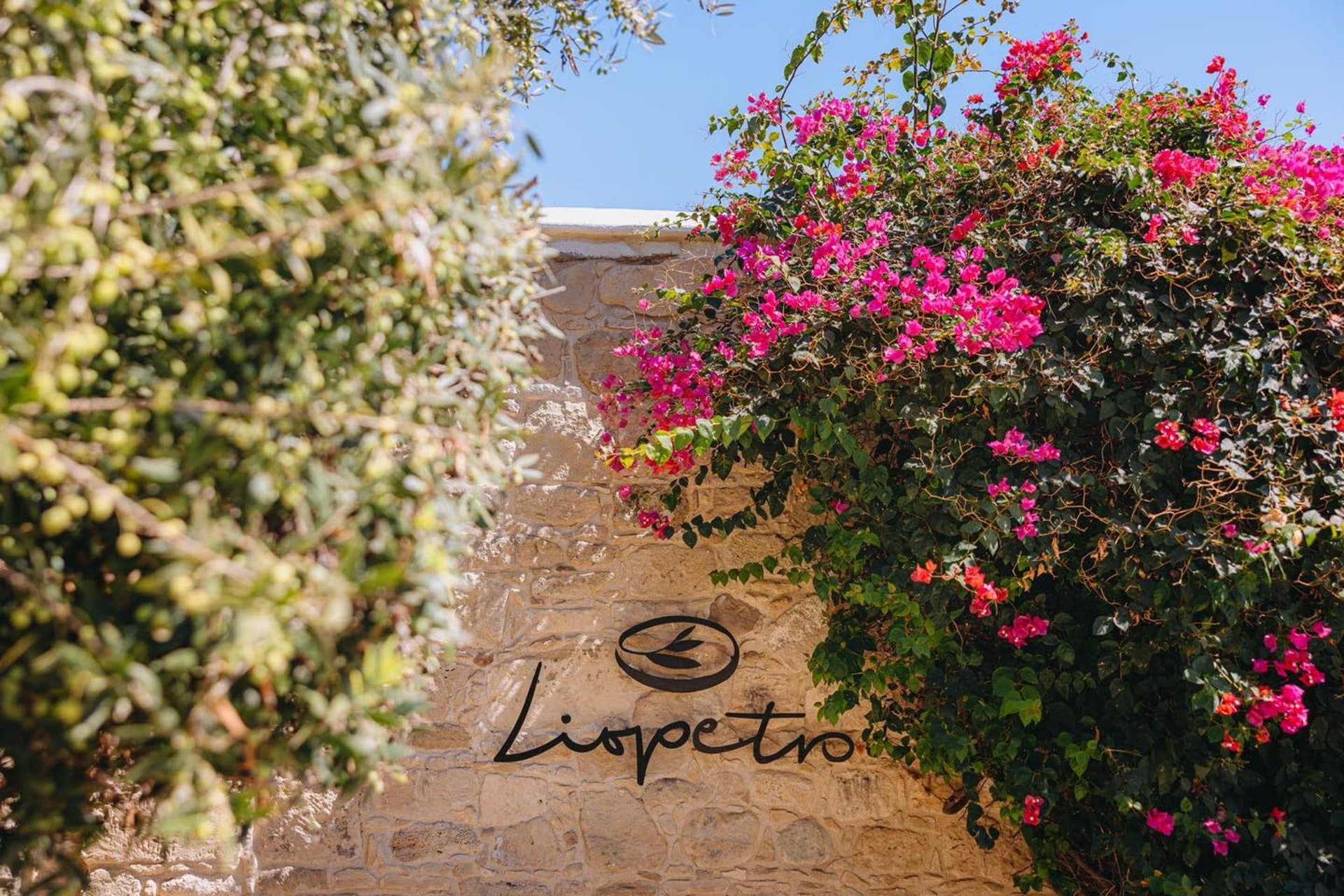 Welcome sign at Liopetro framed by bougainvillea