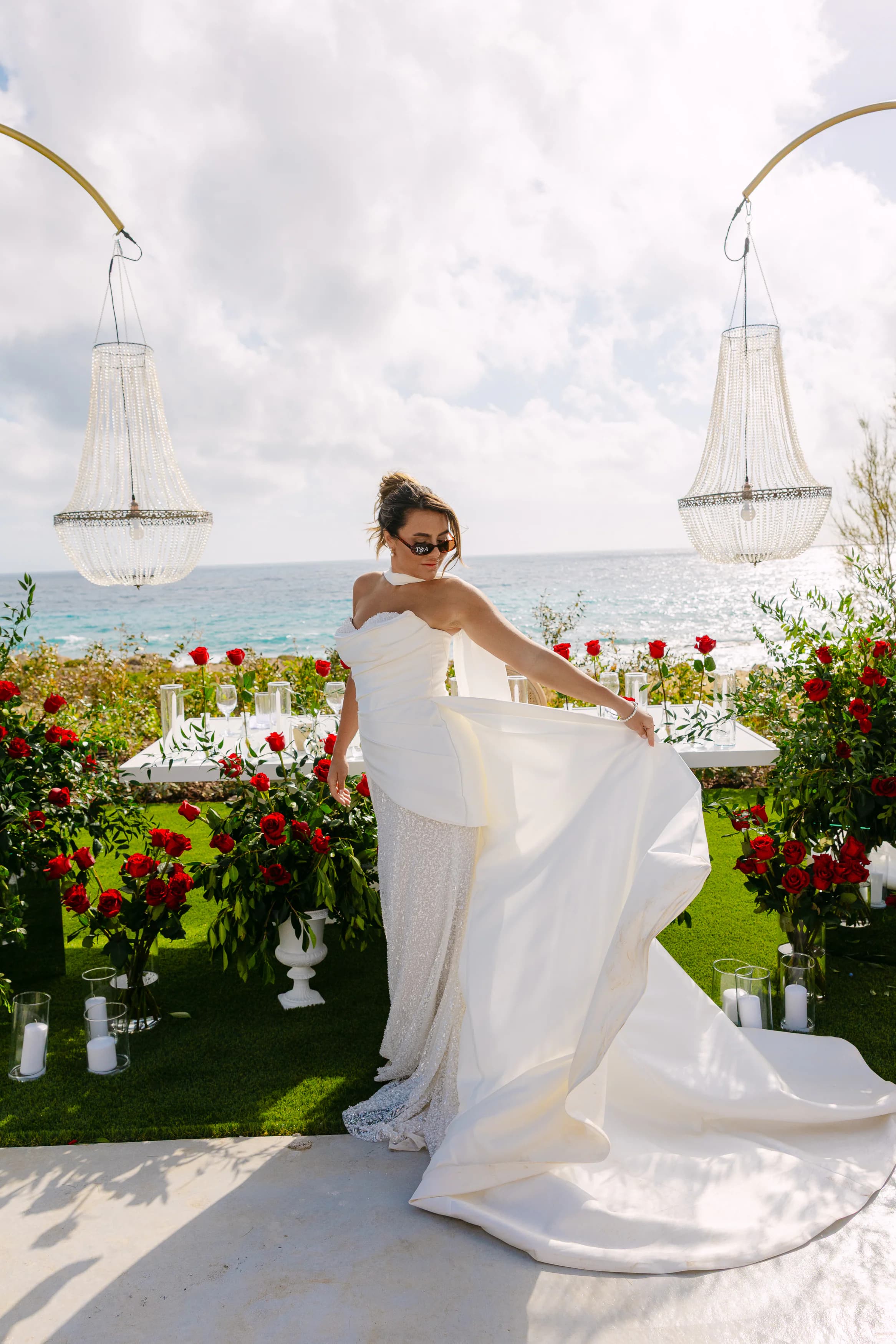 Bride twirling her white ballgown between OZEA's crystal chandeliers and red rose pedestals at Sea Caves Paphos