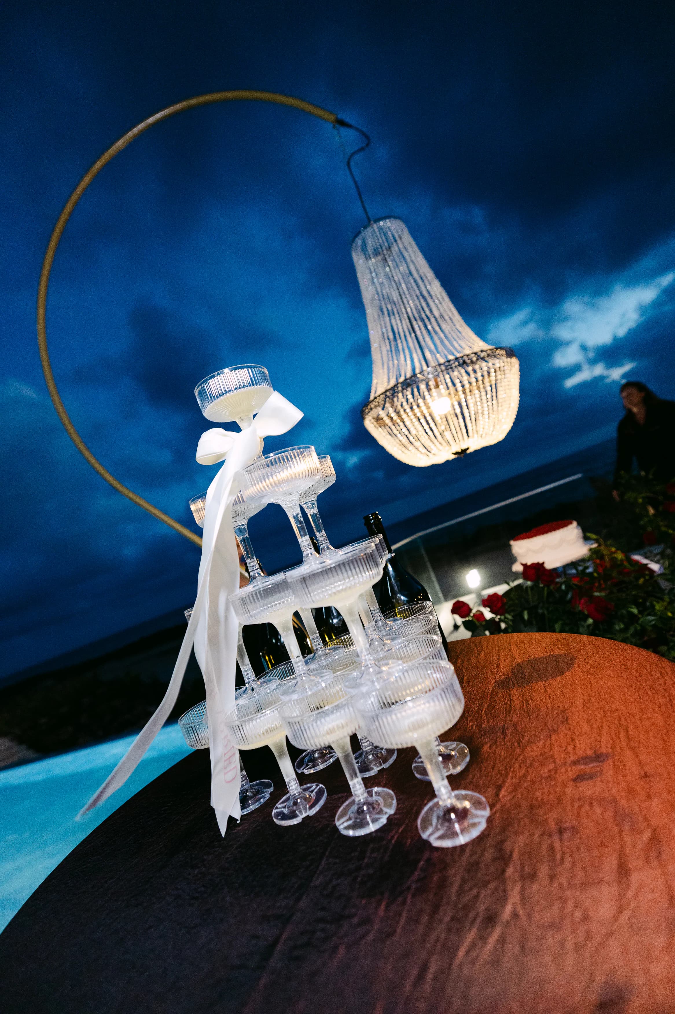 Champagne tower beneath a crystal chandelier at twilight on the OZEA terrace, Sea Caves Paphos